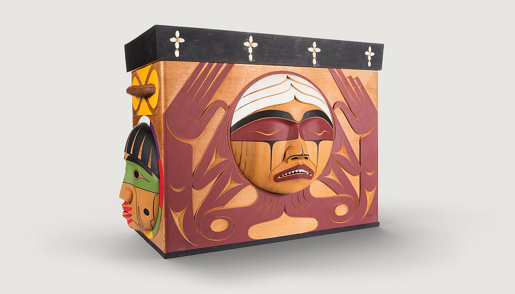 Wooden box with intricately carved faces.
